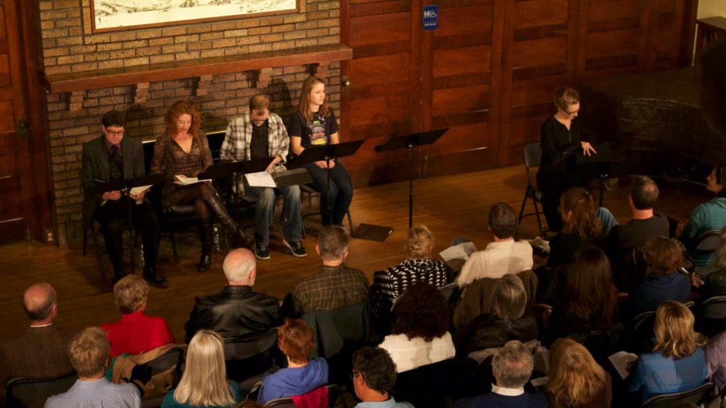 An audience sits for a play reading